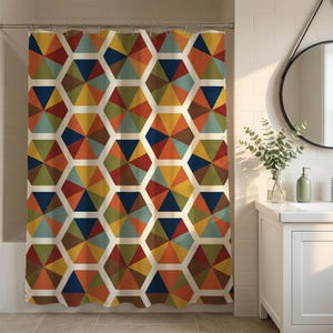 May include: A shower curtain featuring a repeating geometric pattern of hexagons. Each hexagon is divided into six triangular segments in shades of navy blue, mustard yellow, olive green, burnt orange, and teal, separated by white lines.