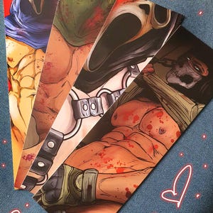 Könnte beinhalten: Eine Sammlung von vier illustrierten Lesezeichen mit muskulösen Figuren mit Horror-Masken und -Bildern. Die Lesezeichen zeigen eine Vielzahl von Farben, darunter Rot, Blau, Grün und Schwarz, mit einem Fokus auf die menschliche Form und Horrorelemente.