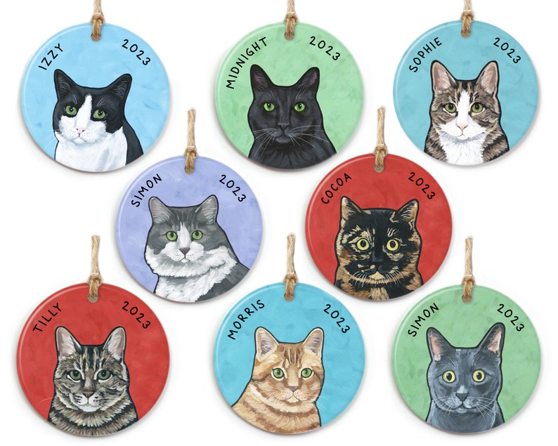 May include: Nine round ceramic ornaments with cat portraits and names. Each ornament has a different cat breed and a different colored background. The ornaments are decorated with the year 2023.