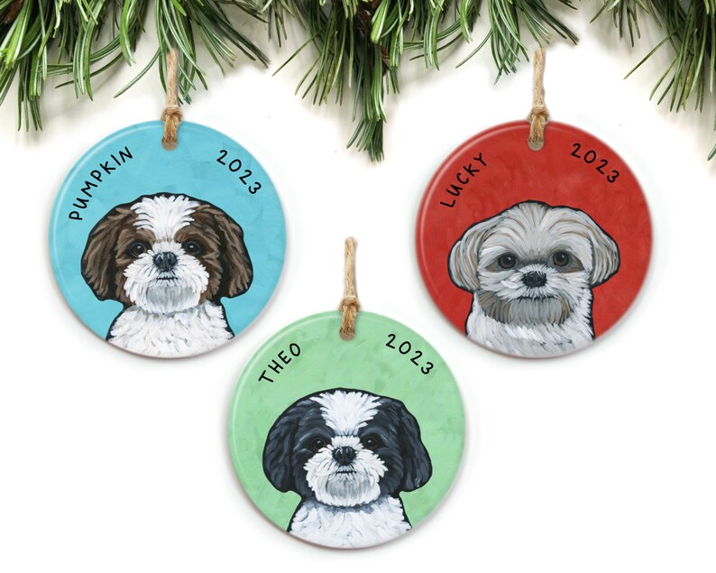 May include: Three round ceramic Christmas ornaments featuring Shih Tzu dogs. Each ornament has a different colored background: blue, red, and green. The dogs are painted in realistic detail. The ornaments are personalized with the names "Pumpkin", "Lucky", and "Theo" and the year "2023".