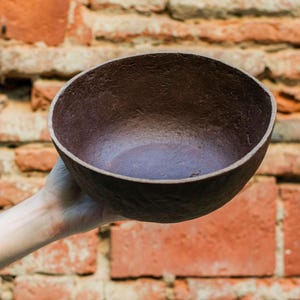 Peut inclure: Un bol ovale brun foncé est présenté devant un mur de briques usé. Le bol a une surface texturée et un intérieur lisse. Le mur de briques est fait de briques rouges et oranges.