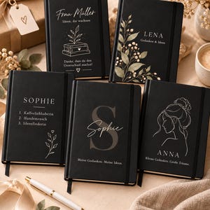 May include: Five black hardcover notebooks with elastic closures and ribbon bookmarks. Each notebook features unique white line art and text, including names like Frau Müller, Lena, Sophie, and Anna, alongside botanical illustrations and personal quotes.