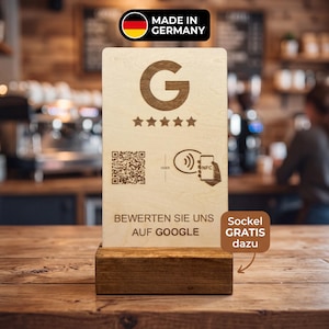 Könnte beinhalten: Ein rechteckiges Schild aus hellem Holz auf einem dunklen Holzsockel mit eingraviertem Google-Logo, fünf Sternen, einem QR-Code und einem NFC-Symbol. Der Text lautet BEWERTEN SIE UNS AUF GOOGLE, ODER, inklusive MADE IN GERMANY Label oben.