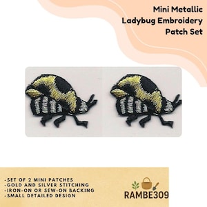 May include: A set of two mini ladybug embroidery patches. Each patch features a black body with gold and silver metallic stitching. The patches have an iron-on or sew-on backing and a small detailed design. The text "Mini Metallic Ladybug Embroidery Patch Set" is visible.