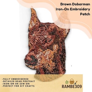 May include: A brown Doberman iron-on embroidery patch featuring a detailed head portrait of the dog. The patch is fully embroidered with shades of brown, tan, and black thread, capturing the facial features and pointed ears of the Doberman.