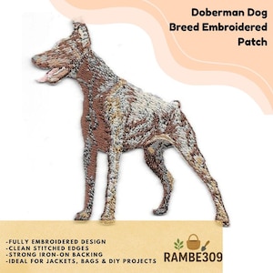 May include: Embroidered patch featuring a Doberman dog in shades of brown and white. The patch has clean stitched edges and an iron-on backing. Text on the patch reads "Doberman Dog Breed Embroidered Patch".