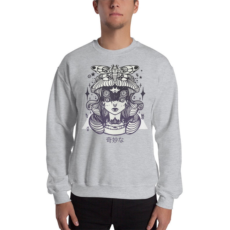 May include: A gray sweatshirt with a graphic print of a woman with a moth on her head. The woman has multiple eyes and is surrounded by stars and a triangle. The text "香妙な" is printed below the graphic.