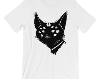May include: A white t-shirt with a black illustration of a cat with multiple eyes. The cat has a third eye on its forehead and a sinister expression.