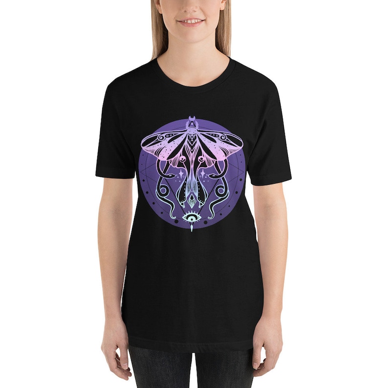 May include: Black t-shirt with a graphic of a moth with a pink and purple gradient, surrounded by a circle with a geometric design and an eye in the center.