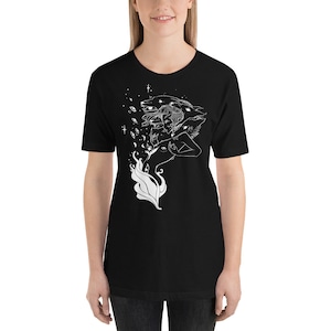 Op de afbeelding: Zwart T-shirt met een wit grafisch ontwerp van een vrouw met meerdere wolfskop en ogen. Het ontwerp is omringd door sterren en andere hemelse elementen.