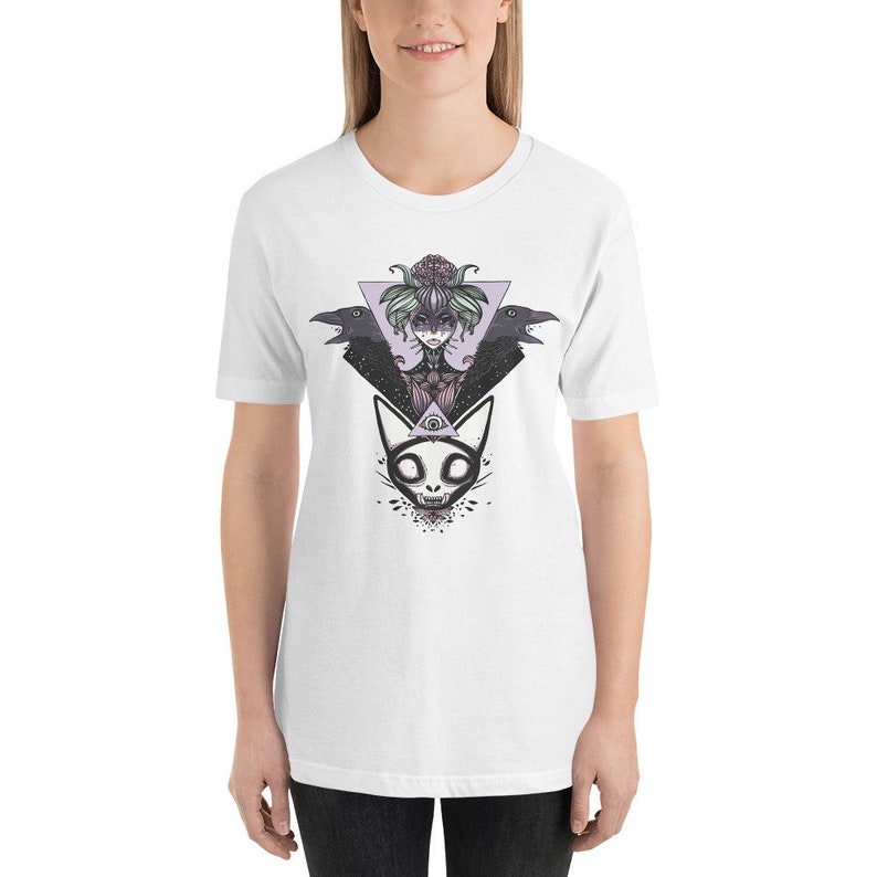May include: White t-shirt with a graphic print of a woman with a floral crown and two ravens, a cat with an all-seeing eye, and a geometric triangle.
