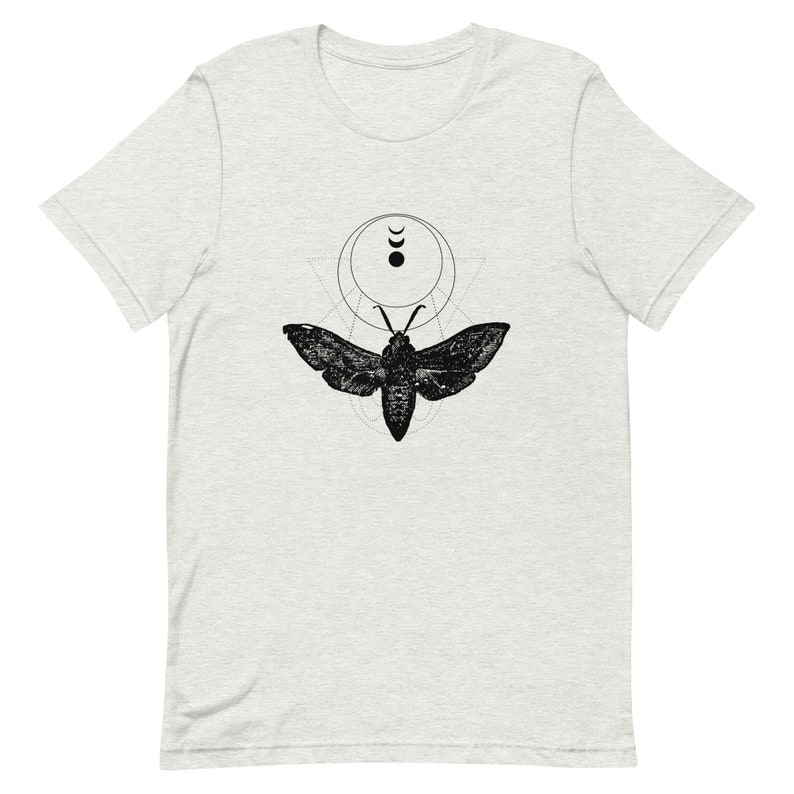 May include: A black and white graphic t-shirt featuring a moth with geometric shapes and crescent moons.