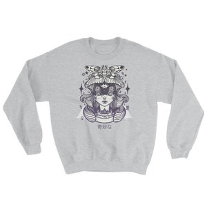 May include: A gray sweatshirt with a black and white illustration of a woman with a moth on her head. The woman has multiple eyes and is surrounded by stars. The text "香妙な" is printed below the illustration.