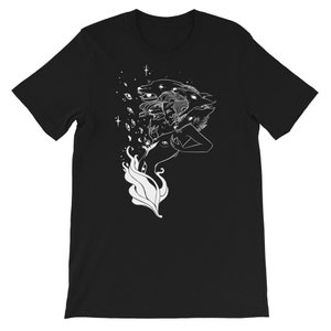 Op de afbeelding: Een zwart T-shirt met een wit grafisch ontwerp van een vrouw met drie wolfskop en een vlam erachter.
