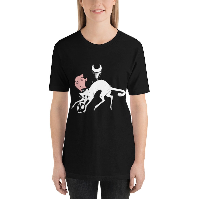 K&ouml;nnte beinhalten: Schwarzes T-Shirt mit einem wei&szlig;en Grafikdruck eines Katers mit einem Sch&auml;del im Maul und einem rosafarbenen Schweinekopf auf seinem Kopf. Die Katze befindet sich unter einem Halbmond.
