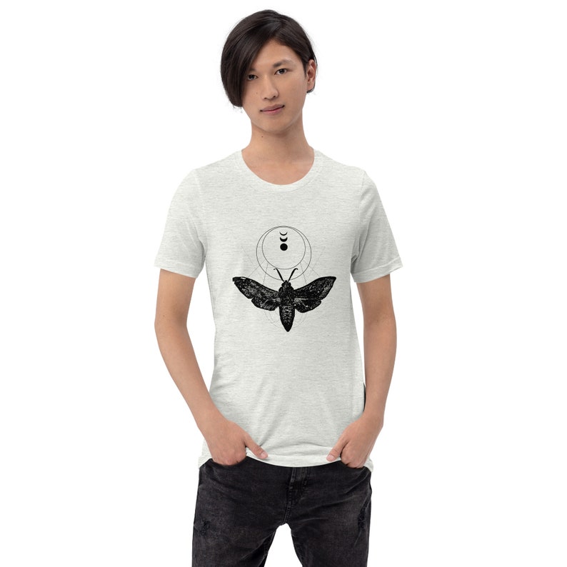 May include: A heather grey t-shirt with a black and white graphic of a moth with geometric shapes and crescent moons.