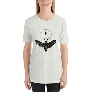 May include: A heather grey t-shirt with a black and white graphic of a moth with a moon and crescent moon design.