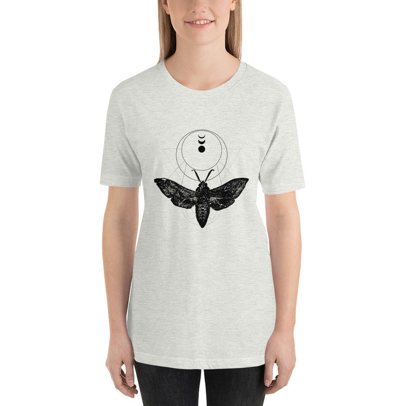 May include: A heather grey t-shirt with a black and white graphic of a moth with a moon and crescent moon design.