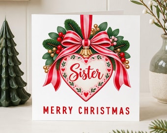 May include: A square white greeting card featuring a heart-shaped ornament illustration with the word Sister in red script. The ornament is adorned with a red and white striped bow, green pine needles, and red berries. The text MERRY CHRISTMAS is below.