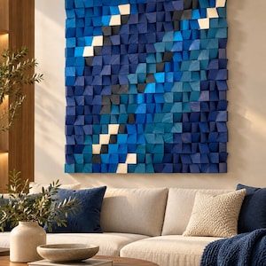 Può includere: Un'opera d'arte da parete quadrata composta da numerosi piccoli blocchi di legno individuali disposti a griglia. I blocchi sono dipinti in varie tonalità di blu navy, blu reale e azzurro, con alcuni blocchi che presentano una finitura in legno naturale.