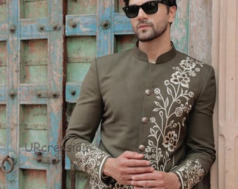 May include: Olive green jacket with floral embroidery on the front and sleeves. The jacket has a mandarin collar and decorative buttons. The model is wearing sunglasses and a cream-colored shirt.