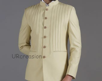 May include: A light beige suit with a mandarin collar and vertical pleats on the front. The suit has a tailored fit with a matching jacket and pants. The jacket features gold-colored buttons and a small pocket. The brand name "URcreasion" is visible.