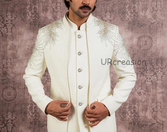 May include: Ivory-colored suit with intricate silver embroidery on the shoulders. The jacket features a mandarin collar and button-down front. The text "URcreasion" is visible on the jacket. The suit is paired with matching trousers.