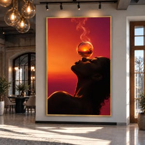 Op de afbeelding: Een verticale rechthoekige wandkunstprint in een gouden lijst met het silhouet van een persoon met het hoofd achterover gekanteld, balancerend op de neus een gloeiende glazen bol. De bol bevat een woestijnzonsondergang met rookpluimen.