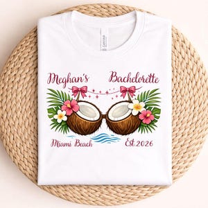 May include: White t-shirt with a tropical design for a bachelorette party. The design includes two coconut halves, flowers, palm leaves, and the text "Meghan's Bachelorette Miami Beach Est. 2026".