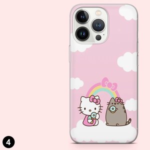 May include: Pink phone case featuring a cartoon illustration of Hello Kitty and a gray cat with donuts, a rainbow, and white clouds. The case has a clear border and a pink background.