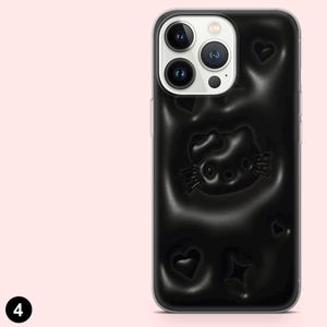 May include: Black smartphone case featuring a raised Hello Kitty design, hearts, and a star. The case has a glossy finish and is designed to fit a smartphone. The case is black with a clear border.
