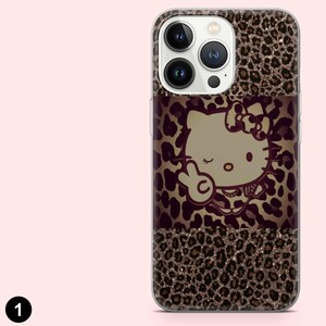 May include: A phone case with a leopard print design and a Hello Kitty graphic. The case has a clear border and a brown, black, and gold color scheme. The Hello Kitty graphic is in the center of the case.