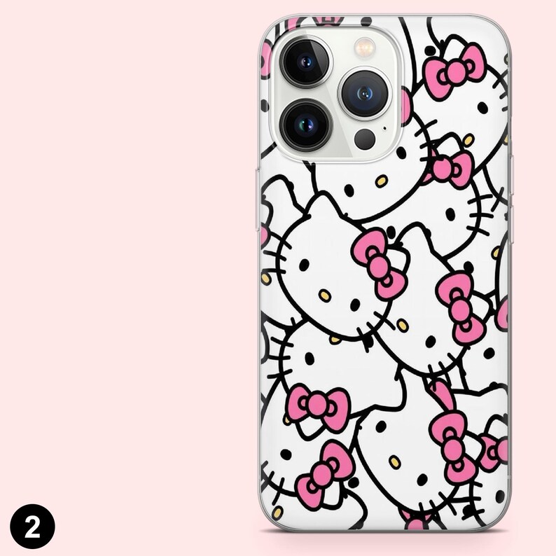 Puede incluir: Una funda transparente para tel&eacute;fono con un patr&oacute;n repetido de caras de gatos de dibujos animados blancos con lazos rosas y contornos negros. La funda tiene recortes para la c&aacute;mara y los botones del tel&eacute;fono.