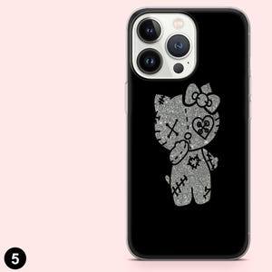 Puede incluir: Funda de tel&eacute;fono negra con un dise&ntilde;o de gato de dibujos animados plateado con purpurina, detalles cosidos, un lazo y un coraz&oacute;n. La funda tiene un borde transparente y un fondo negro. Un accesorio &uacute;nico y llamativo.
