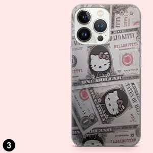 May include: Clear phone case featuring a design of dollar bills with Hello Kitty illustrations. The case has a clear border and covers the back and sides of the phone. The design includes the text "HELLO KITTY".