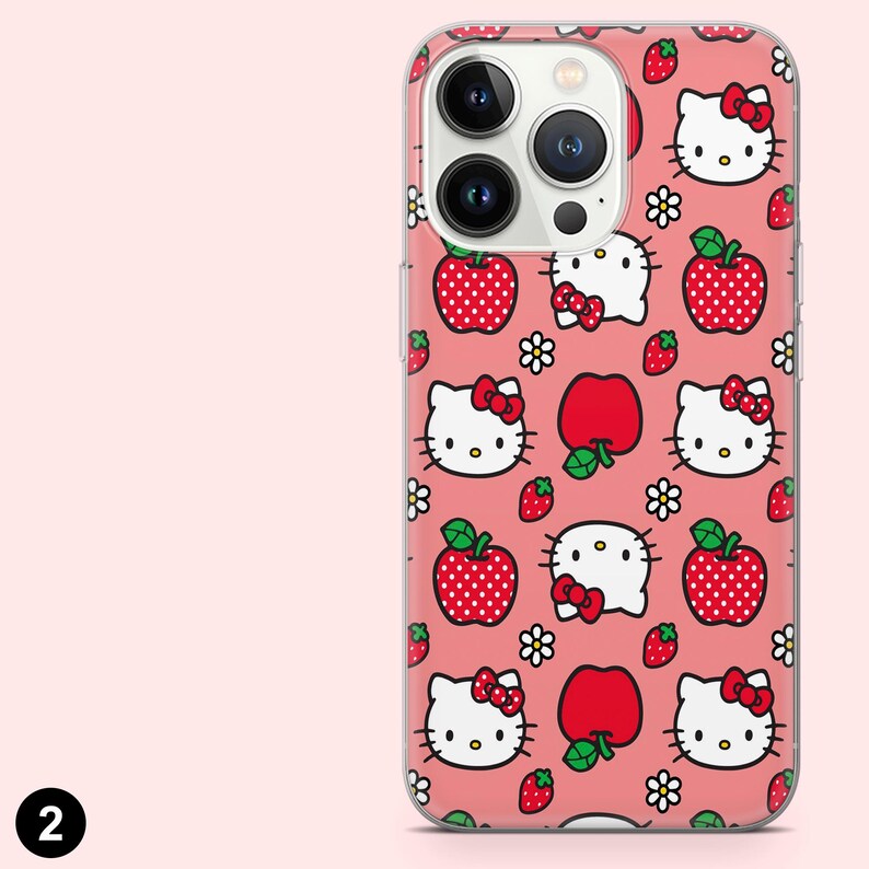 May include: A clear phone case featuring a repeating pattern of Hello Kitty faces with red bows, red apples with green leaves, strawberries, and white flowers on a pink background. The phone case has a camera cutout.