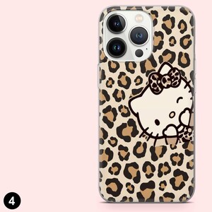 May include: A clear phone case featuring a leopard print pattern with brown spots on a beige background. The case has a white Hello Kitty graphic with a bow. The case has cutouts for the phone's camera and buttons.