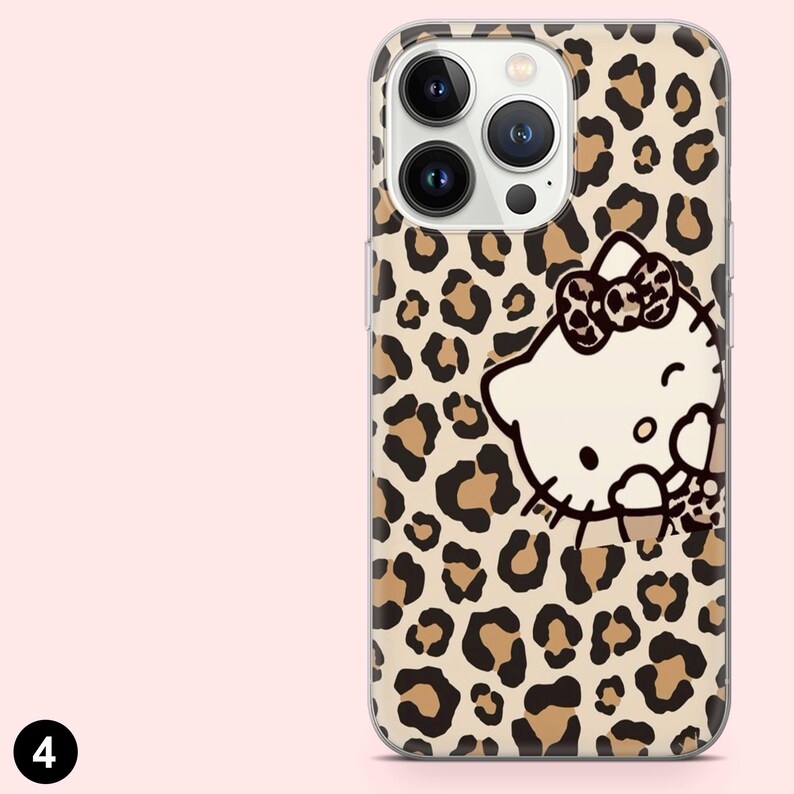 May include: A clear phone case featuring a leopard print pattern with brown spots on a beige background. The case has a white Hello Kitty graphic with a bow. The case has cutouts for the phone's camera and buttons.