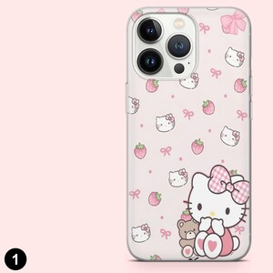 May include: A clear phone case with a pink background featuring a pattern of Hello Kitty faces, strawberries, and bows. The case has a large Hello Kitty character with a teddy bear. The case is designed for a smartphone.