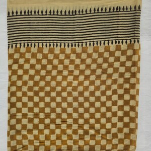 May include: A rectangular textile with a beige top section, a black striped middle, and a brown and beige checkered pattern. The fabric appears to be lightweight and suitable for a scarf or shawl.