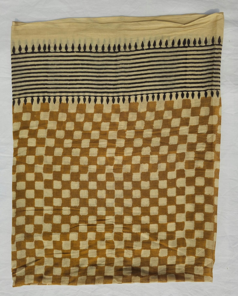 May include: A rectangular textile with a beige top section, a black striped middle, and a brown and beige checkered pattern. The fabric appears to be lightweight and suitable for a scarf or shawl.