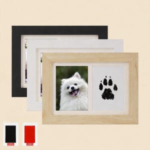May include: Three picture frames in black, white, and natural wood. The natural wood frame contains a photo of a white dog and a black paw print. Two ink pads, black and red, are at the bottom of the image.