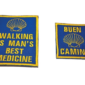 Può includere: Due toppe di tessuto blu con conchiglie di capesante ricamate in giallo e testo. La toppa più grande dice "Walking is Man's Best Medicine". La toppa più piccola dice "Buen Camino".