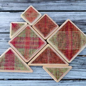 Könnte beinhalten: Ein Satz von sieben geometrischen Holzformen mit einem roten, grünen und braunen gewebten Muster. Die Formen sind ein Quadrat, ein Dreieck und eine Raute.