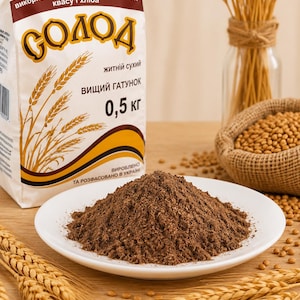 May include: A white bag of dry rye malt labelled with the text "СОЛОД" and "0,5 кг" featuring wheat illustrations, alongside a white plate piled with dark brown ground malt powder and scattered grains of wheat on a wooden surface.
