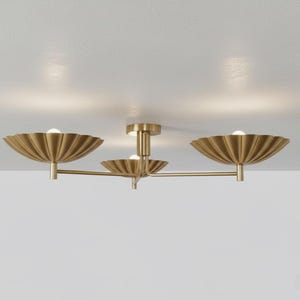 Könnte beinhalten: Eine goldfarbene Deckenleuchte mit drei Lichtern und modernem Design. Die Leuchte verfügt über drei dekorative, fächerförmige Schirme, die jeweils eine Glühbirne beherbergen. Die Leuchte ist an einer weißen Decke montiert.