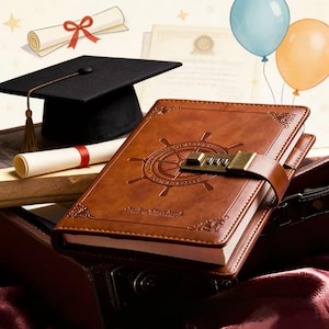 May include: A brown leather journal with a combination lock, embossed with a ship's wheel design. A graduation cap, diploma, and balloons are in the background, suggesting a graduation theme.