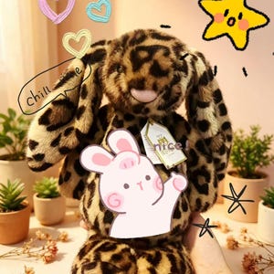 May include: A plush toy bunny with a leopard print pattern. The bunny has long floppy ears and a tag that says "nice!". Decorative hearts and a star are drawn in the background. A speech bubble says "chill".
