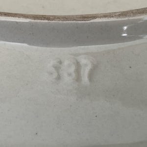 May include: Close-up of a white ceramic bowl with a slightly textured surface. The rim is a darker shade of white. The number "381" is embossed on the bowl's surface.