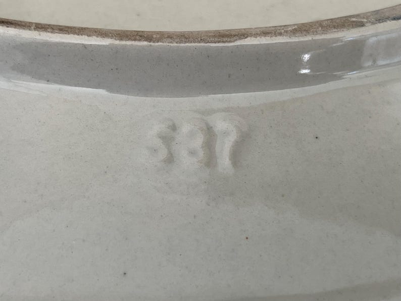 May include: Close-up of a white ceramic bowl with a slightly textured surface. The rim is a darker shade of white. The number "381" is embossed on the bowl's surface.